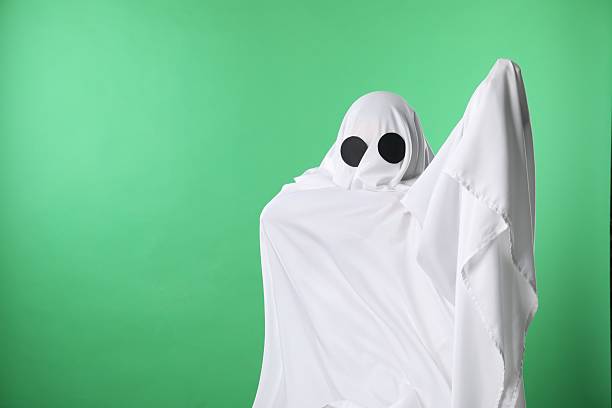 Creepy ghost. Person covered with white sheet on green background, space for text