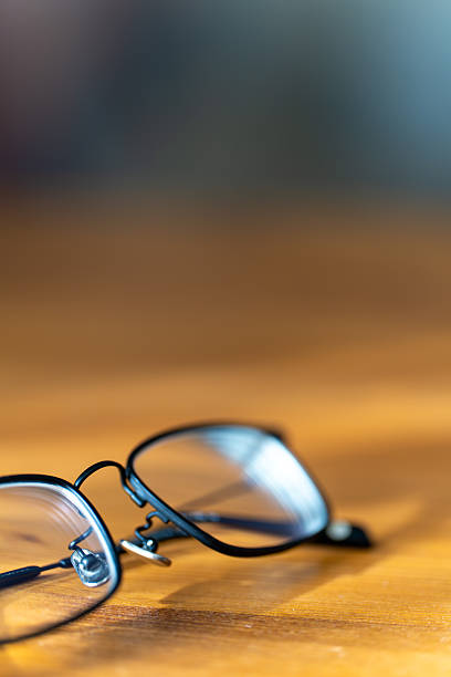 istock Black rimmed eyeglasses on wooden table in sunlight 2252632984