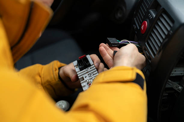 Technician connects wires and checks the system inside a car during cold weather