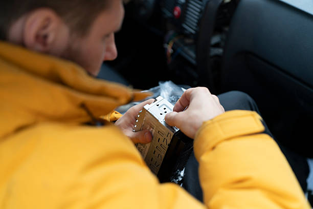 istock A person works on fitting a car stereo while seated inside a vehicle. Tools are nearby 2252633311
