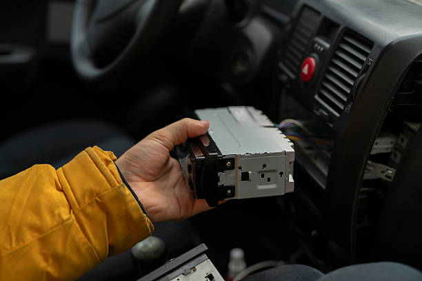 istock A person holds a car stereo while working inside a vehicle in a garage 2252633314