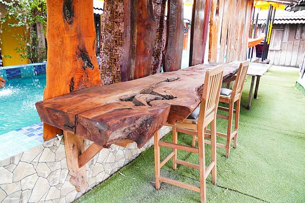 Cafe with wooden tables and chairs. table and chairs made of teak wood in a restaurant. teak wood is famous for its good quality for furniture. long rustic bar table made from a single solid slab