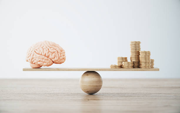 istock Human Brain and Gold Coin Stack On Wooden Seesaw. 2252641624