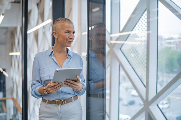 istock Businesswoman holding digital tablet looking out office window 2252643444