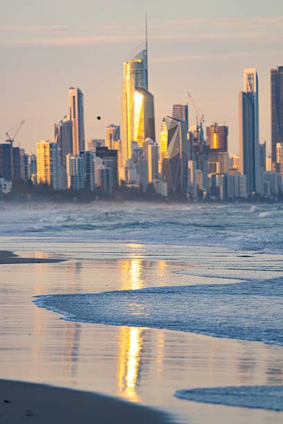 istock Blue ocean waves roll toward a beach at sunset beneath a yellow sky with Surfers Paradise city in the distance 2252644057