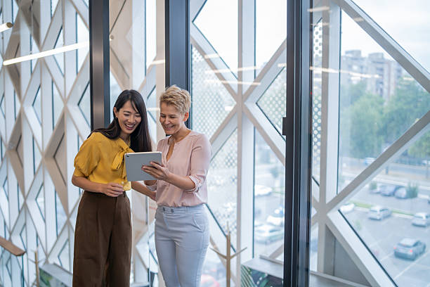 istock Businesswomen smiling and using digital tablet in modern office 2252645215