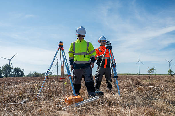 istock Engineer working at renewable energy site wind turbines examining  blueprint surveying instrument mounted tripod ensuring accurate land measurements practices in environmental industrial. 2252645300