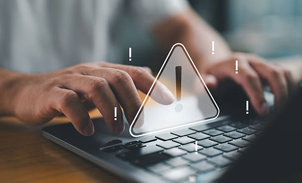 istock A person typing on a laptop with a warning sign overlay, signifying cybersecurity risks, data breaches, and the importance of online security. 2252647164
