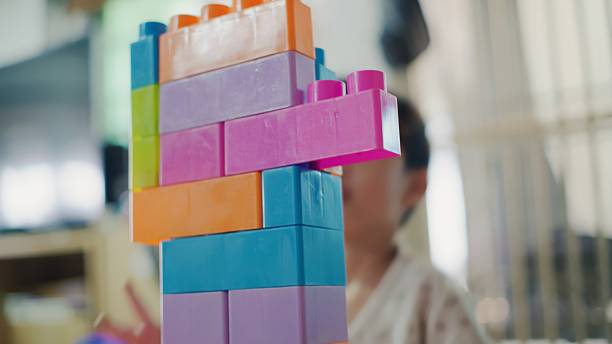 Four-year-old child plays with colorful plastic building blocks, creating towers, vehicles, and imaginative structures. The scene highlights creative play, early learning, and the development of imagination, problem-solving, and fine motor skills during preschool-age playtime.