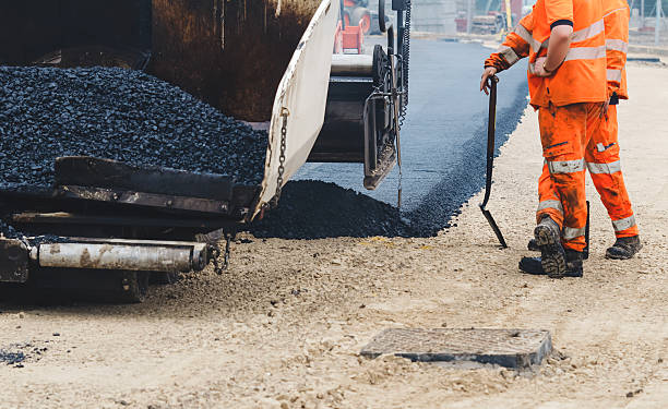 istock Construction road workers in orange uniform laying hot asphalt on roadway 2252655326