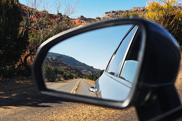 istock Road reflected in car side mirror. Scenic mountain drive perspective. Asphalt highway behind vehicle. 2252658622