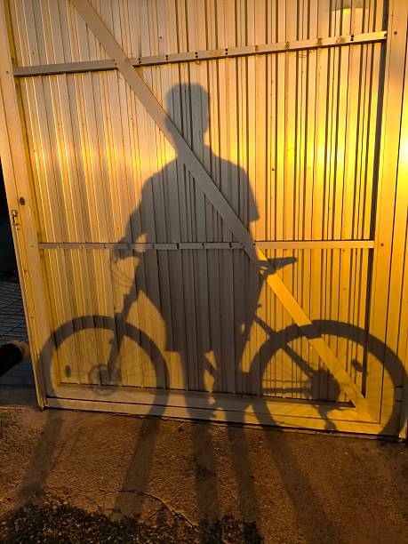 shadows in a wall of a man in a bicycle during a summer sunset