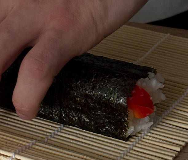 istock A hand is skillfully rolling sushi with rice and vibrant vegetables on a bamboo mat 2252662968