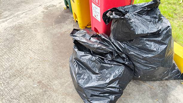 istock Black garbage bags placed on the pavement next to colorful sorting trash bins 2252664368
