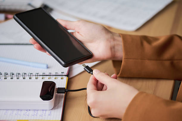 istock Woman Connecting Smartphone to Power Bank While Studying 2252664748