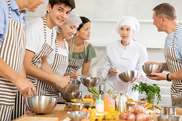 istock Female chef giving instructions to students standing around table in cooking class 2252666942