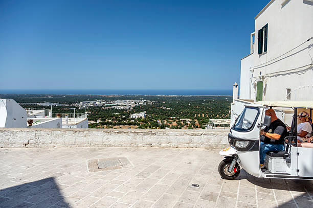 Ostuni, Apulia, Italy - June 27, 2025: A motor trike carrying tourists drives through the old town of Ostuni. The so-called White City in Apulia is very popular with tourists.