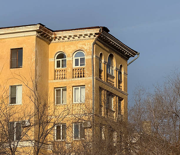 This photograph captures the detailed facade of a historic multi-story building, showcasing rows of evenly spaced rectangular windows framed by elaborate arched moldings and decorative cornices. The symmetrical design highlights classical architectural elements, including pilasters and ornate detailing along the upper levels and ground-floor arches. No people are present, emphasizing the structure's timeless elegance and intricate craftsmanship. The image evokes a sense of historical grandeur in an urban environment, suitable for commercial uses such as illustrating architecture articles, urban planning reports, book covers on European history, editorial content about cityscapes, or backgrounds in media productions focused on heritage preservation and classical design.