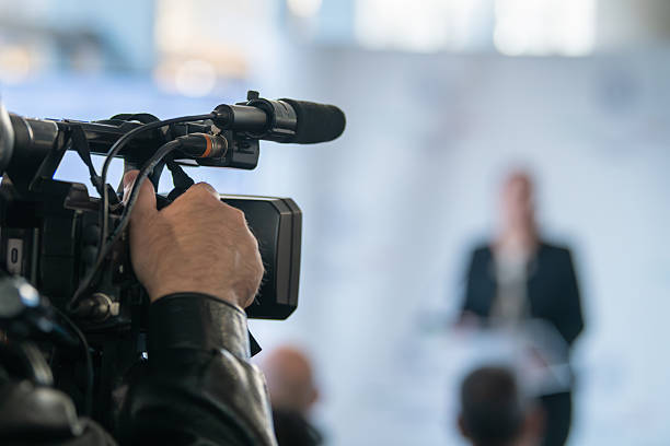 istock TV camera focused on podium during press briefing. Highlights communication accuracy, media presence, and organized public message delivery. 2252669119