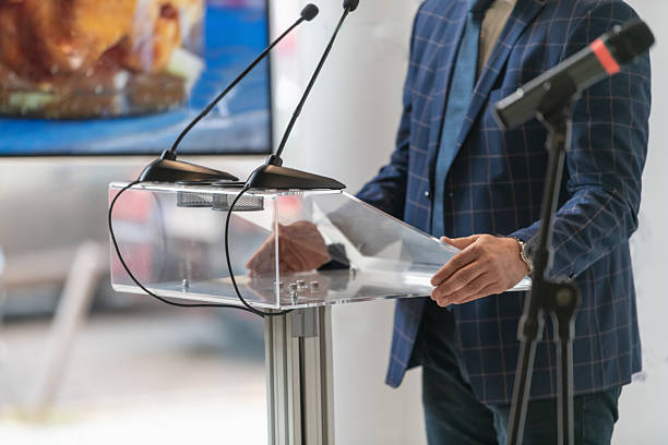 istock Male speaker delivering formal statement on stage during press conference. Highlights communication clarity, media presence, and structured public setting. 2252669286
