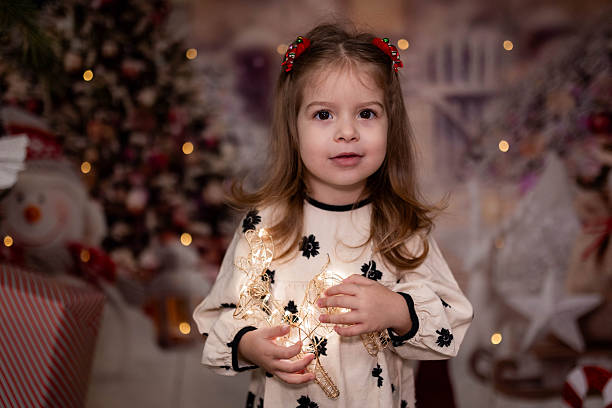 Little girl sitting in a festive indoor setting decorated for Christmas.