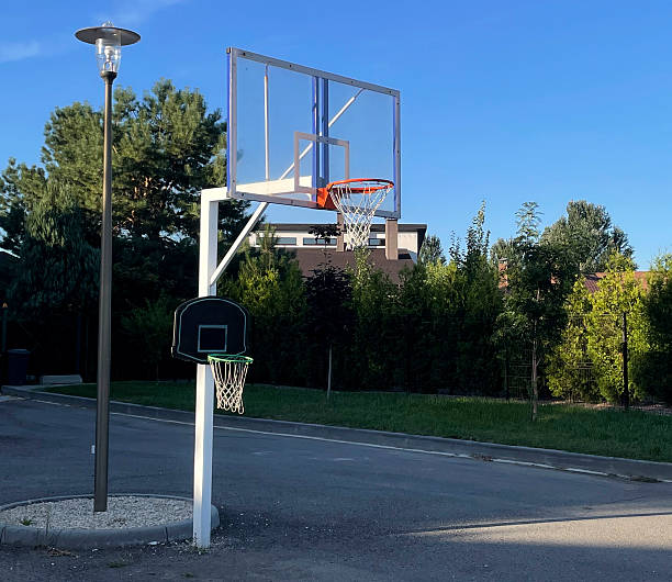 istock Two basketball hoops stand on a quiet street surrounded by trees under a sunny sky 2252670607