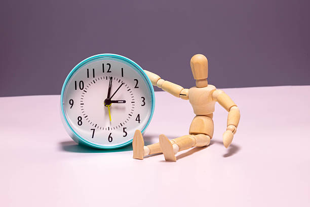 istock white vintage alarm clock and wooden mannequin behind 2252670880