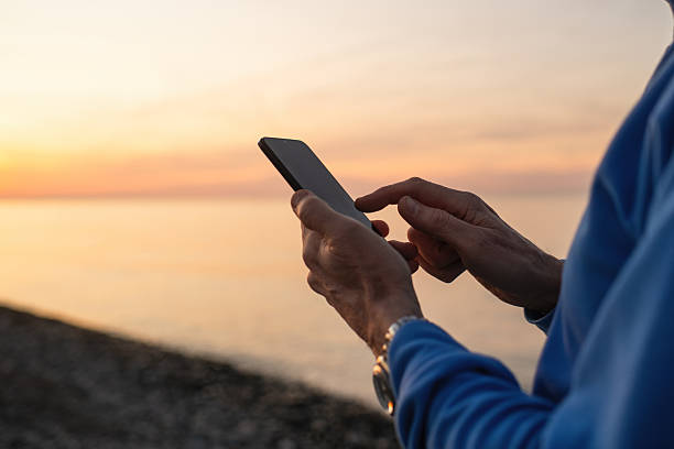 istock Senior man with smartphone enjoying sunset on the beach 2252674332