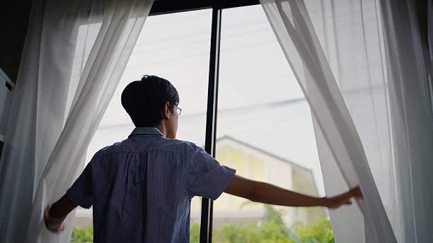 istock Asian Man Opening Window Curtains for a Fresh and Calm Workday. 2252676890