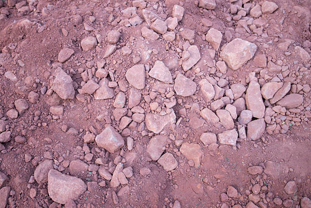 Texture of red soil with small stones, natural background, top view