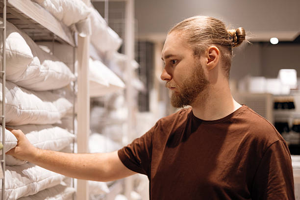 istock Young man selecting a pillow in a home goods store, testing comfort, softness. 2252677860
