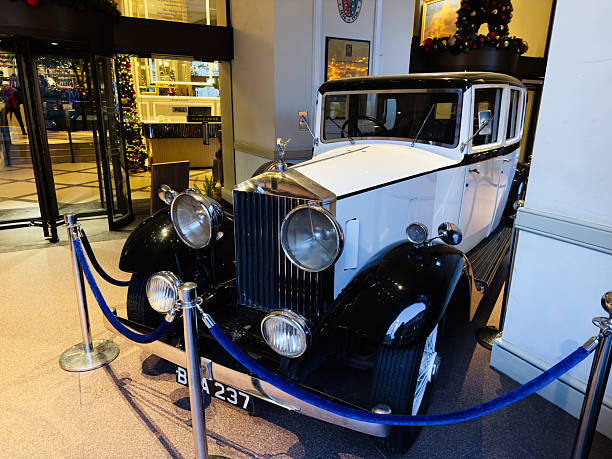 Manchester, UK - December 10, 2025: Classic white and black vintage Rolls Royce car showcased in a festive Manchester hotel lobby with Christmas decor.