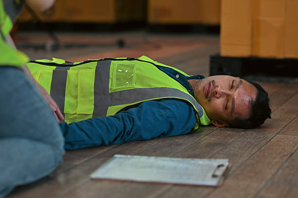 istock Industrial accident scenario showing a fallen worker on the warehouse floor, emphasizing safety risks and the importance of immediate medical assistance 2252680254