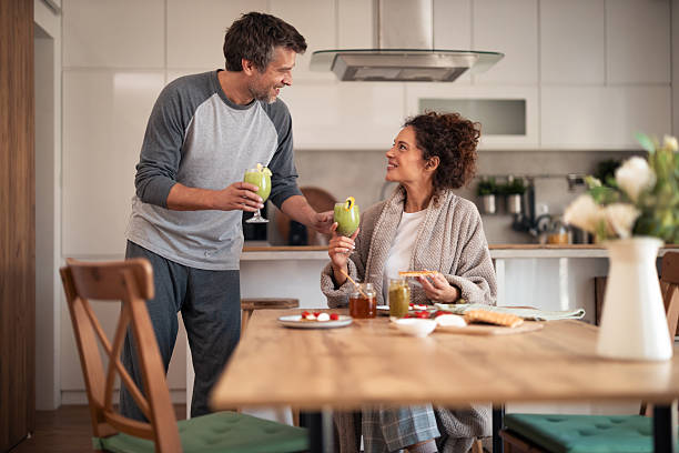 istock Happy Couple Toasts With Green Smoothies At Breakfast Table In Modern Kitchen 2252680960