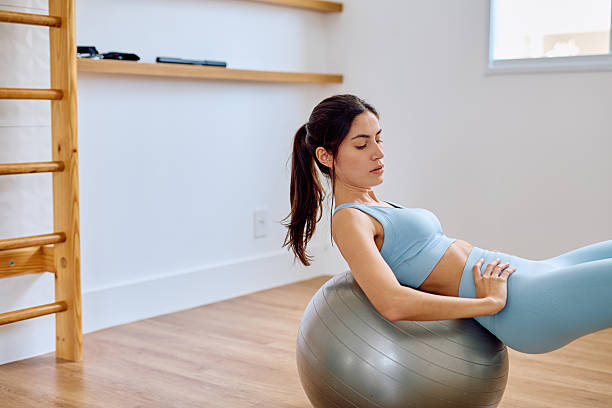 istock Woman exercising core muscles using stability ball at home 2252681305