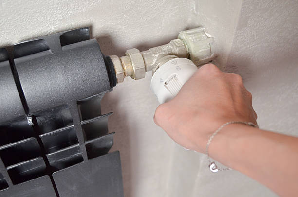 istock Woman's hand adjusting radiator thermostat valve at home 2252682097