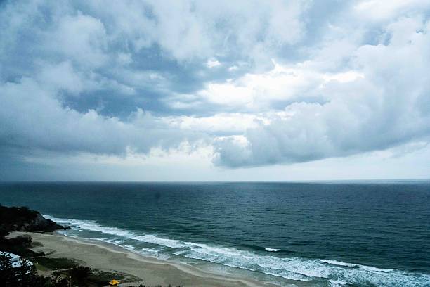Green tropical forest at seashore, white sand beach, white foam from waves breaking water edge