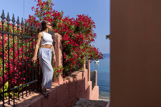 Beautiful mid adult woman enjoys exploring Mediterranean island on a warm, sunny summer day. A simple moment of relaxation and travel.