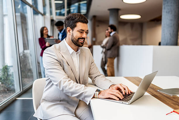 istock Smiling young businessman working on laptop in modern office 2252684605