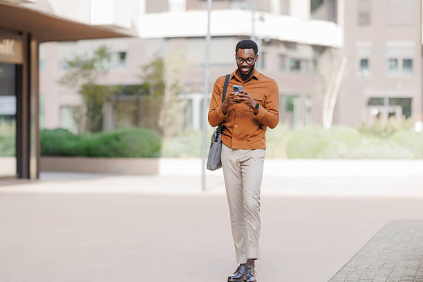 istock Young man walking outdoors with smartphone 2252684637