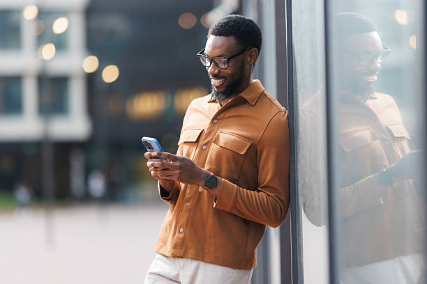 istock Young man in casual outfit, standing outdoors, smiling and using smartphone 2252684674
