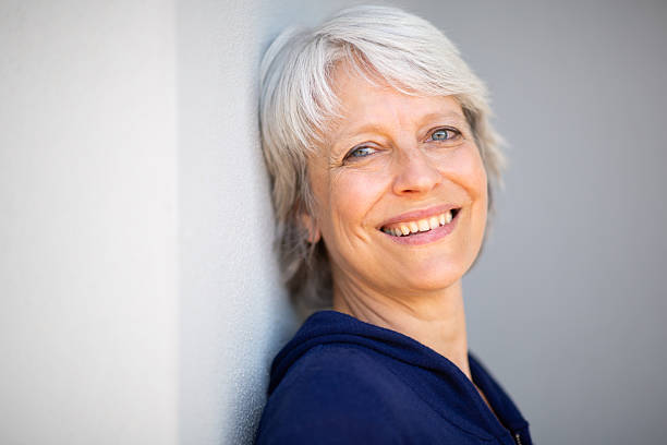 istock Mature woman leaning against wall and smiling 2252684731