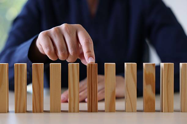 istock Risk. Woman pointing at domino tale at table, closeup 2252686480