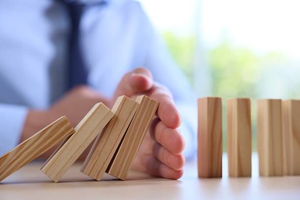 istock Risk. Man stopping domino effect at table, closeup 2252686496