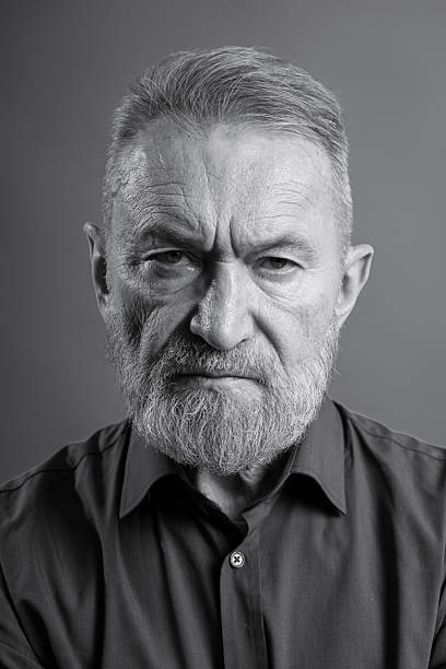 Senior adult man with gray beard gazing intensely, expressing seriousness and deep emotion