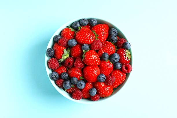 istock Different fresh ripe berries in bowl on color table, top view 2252689492