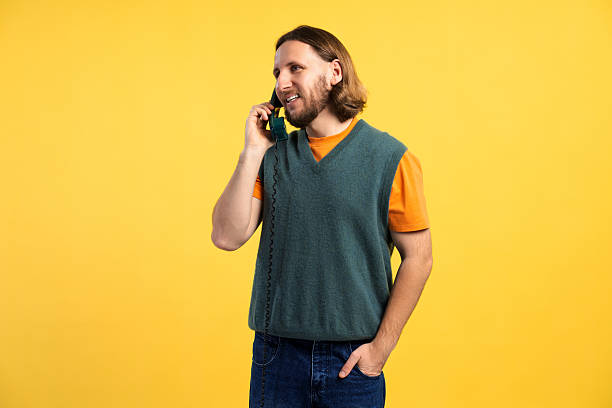 Cheerful male holding vintage telephone, communicating with hand in pocket