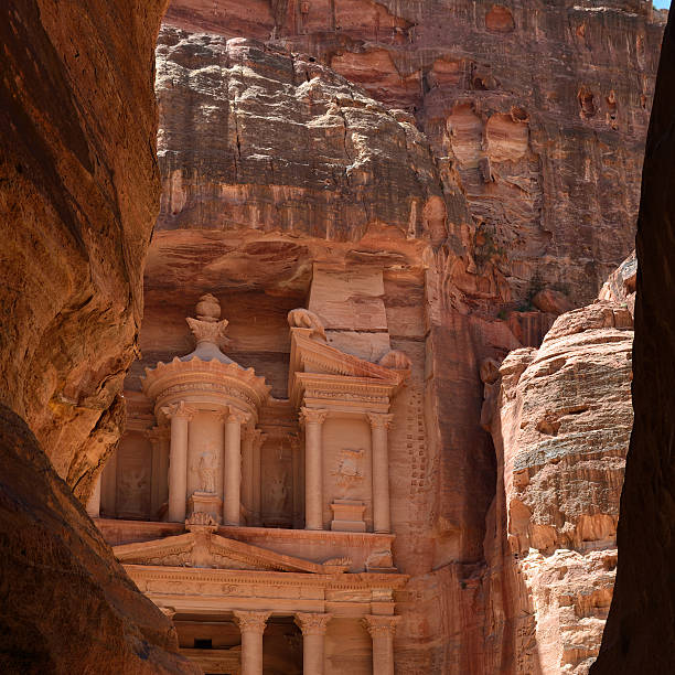 Silhouette  of two tourists walking along the Siq entering the lost city of Petra.