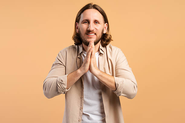 istock Man smiling, making namaste or prayer gesture, looking hopeful and grateful 2252692054