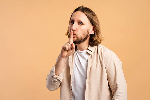 istock Young man making silence gesture with finger on lips, asking for quiet or keeping secret 2252692061